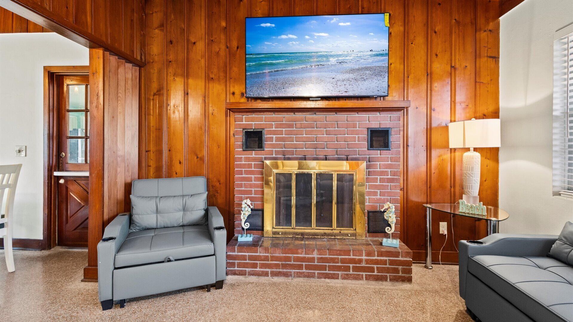 Ein Wohnzimmer mit Kamin, einem darüber angebrachten Fernseher und zwei Sofas.