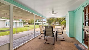 A covered patio with a table and chairs, a ceiling fan, and a view of a residential area. - 2BR Coastal Cottage Near Downtown & Beaches (Vero Beach)