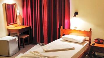 Ein Hotelzimmer mit Bett, Schreibtisch, Stuhl, kleinem Kühlschrank und Telefon.