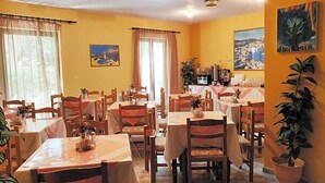 Un comedor con mesas y sillas, una cafetera y vistas a un pueblo costero.