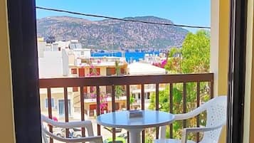 Ein Balkon mit Tisch und Stühlen, mit Blick auf eine Stadt, Gebäude und einen Hügel.