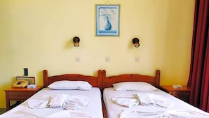 Habitación de hotel con dos camas, un cuadro en la pared y un teléfono en la mesita de noche.