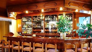 Un área de bar con taburetes de madera, un espejo grande y estantes con botellas de licor.