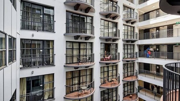 A multi-story building with balconies, large windows, and a modern architectural design.