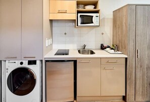 Een kleine keuken met een wasmachine, een magnetron en een spoelbak.