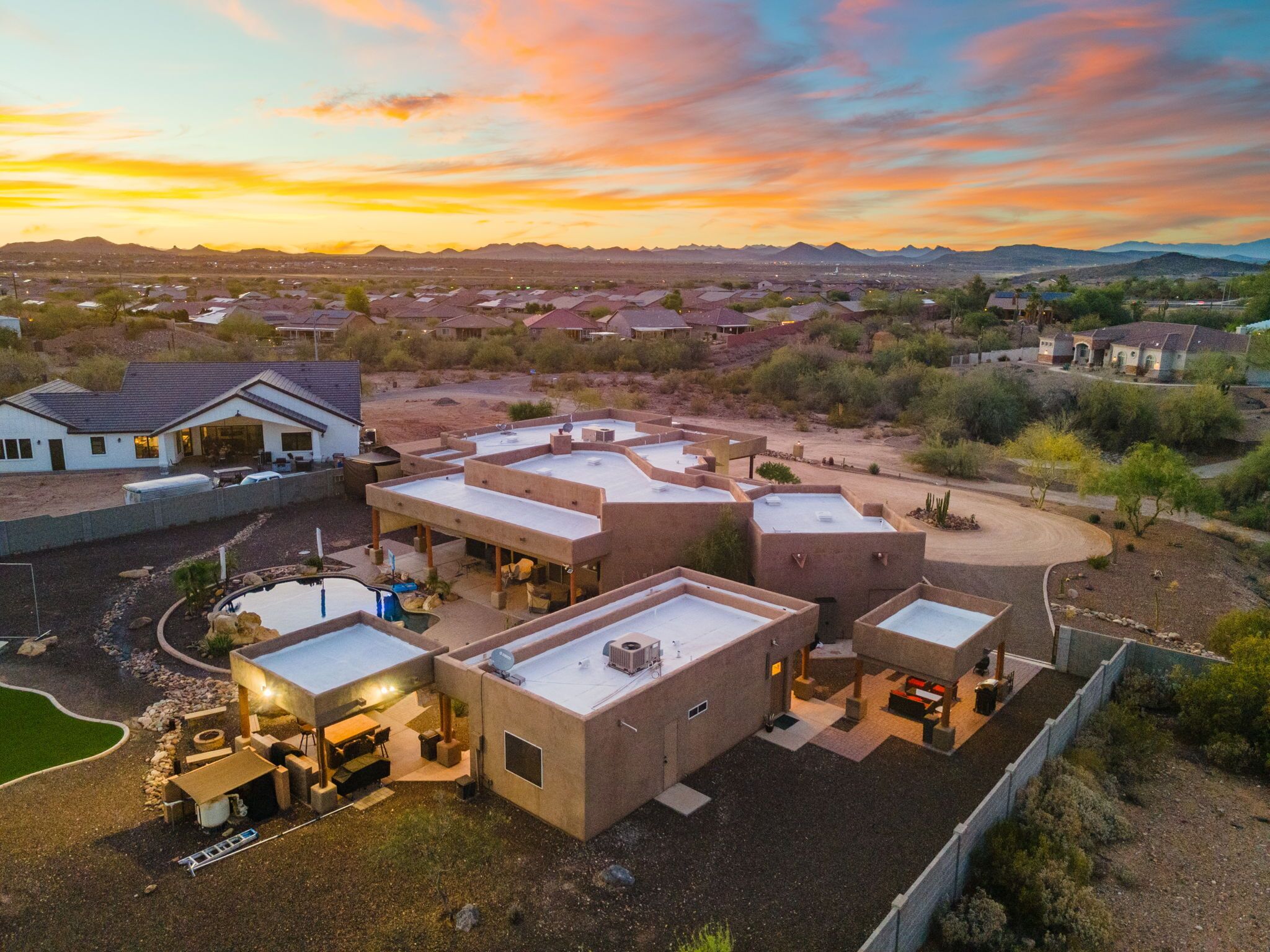 A residential area with multiple houses, a swimming pool, and a clear view of distant mountains.
