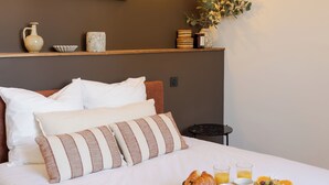 A neatly made bed with pillows, a bedside table with a glass of orange juice, and a tray with croissants and fruit. - Tour Vinea - Private Jacuzzi & 4K Cinema near Bordeaux (Villenave-d'Ornon)
