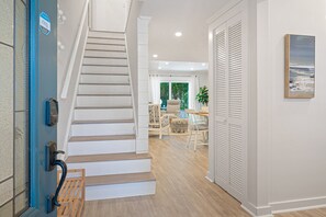 A staircase leading to a living area with a dining table and chairs, a potted plant, and a view of the outdoors. - Pet Friendly, Coastal Condo Near Folly Field Beach (Bluffton)