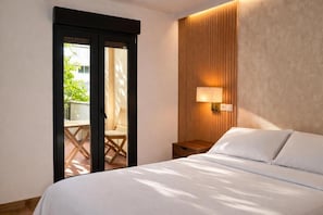 A hotel room with a bed, a nightstand, a lamp, a sliding door to an outdoor area, and a wooden wall panel. - Collection Las Ventas (Madrid)