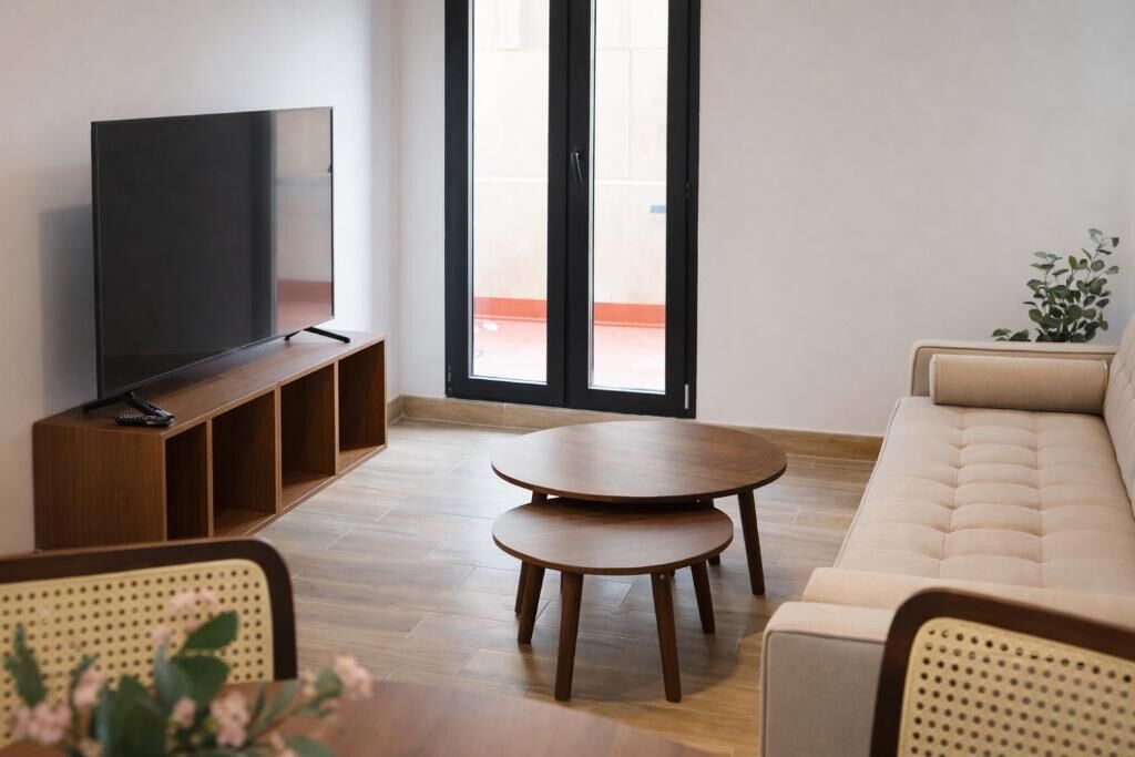 A living room with a TV, a sofa, a coffee table, and a dining table.
