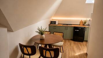 Una cocina compacta con zona de comedor, microondas, refrigerador y una planta en maceta.