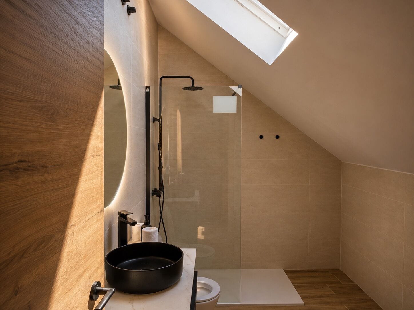 Un baño moderno con tragaluz, ducha, inodoro y lavamanos.