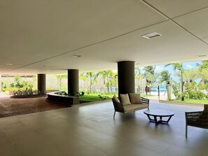 A spacious indoor area with a pool, outdoor seating, and a view of the ocean. - Falésia Seixas – Charme à Beira-Mar (João Pessoa)