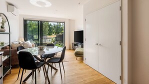 Una sala moderna con comedor, ventanas amplias, televisor de pantalla plana y vistas al exterior.