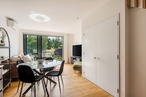 A modern living room with a dining area, large windows, a flat-screen TV, and a view of the outdoors. - Relaxing Wānaka Townhouse (Wānaka)