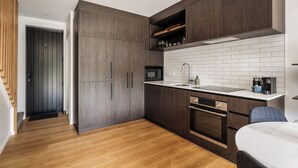 Una cocina moderna con armarios de madera oscura, un salpicadero de azulejos blancos y un horno empotrado.