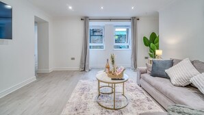 Een moderne woonkamer met een bank, een salontafel en een groot raam met gordijnen.