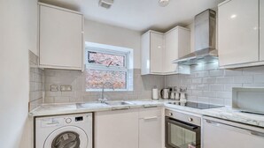 Een moderne keuken met een ingebouwde wasmachine, oven en een raam met uitzicht op een gebouw van baksteen.