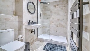 Een badkamer met toilet, wastafel, douche en een handdoekhouder.