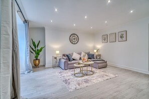 Uma sala de estar moderna com um sofá, uma mesa de centro, uma planta em vaso e um relógio de parede.