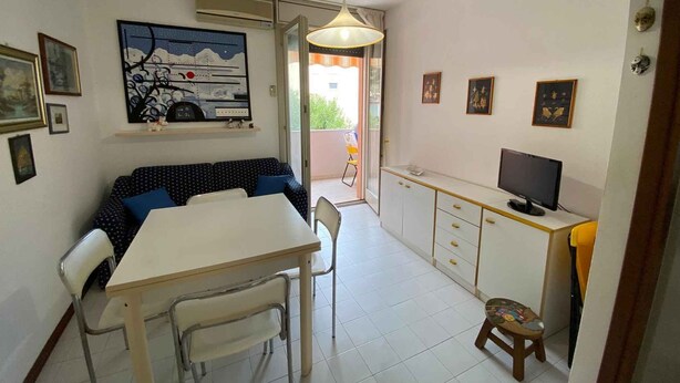 Een kleine leefruimte met een eethoek, een kitchenette en een balkon.