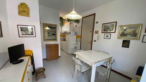 Een knus woongedeelte met een eethoek, kitchenette en een televisie.