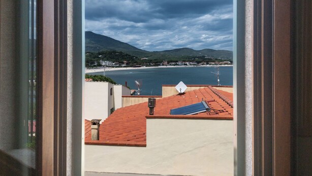 Vista desde una ventana a una zona costera con edificios y una masa de agua.