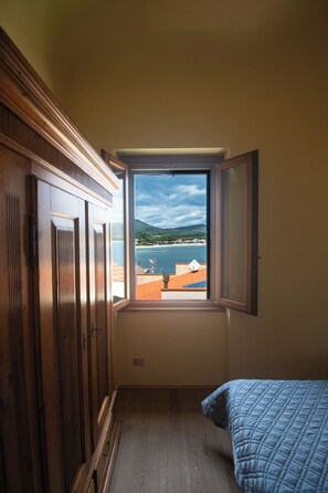 Ein Schlafzimmer mit Blick aus dem Fenster auf einen Strand und Hügel.