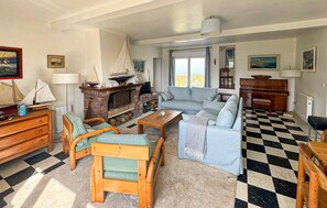 Ein Wohnzimmer mit Kamin, einer Couch, einem Couchtisch und einem Schachbrettmuster-Boden.