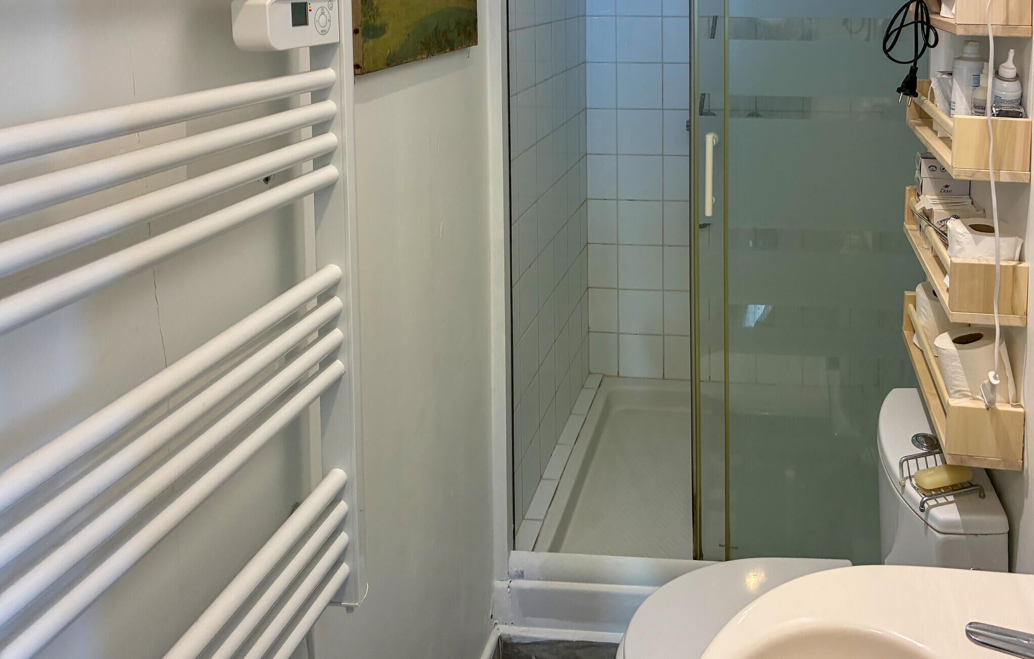 Ein Badezimmer mit Duschkabine aus Glas, Toilette und Waschbecken in Weiß.