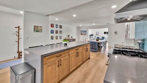 Una cocina moderna con una isla central, armarios de madera y una campana extractora de acero inoxidable.