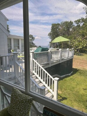 Une terrasse extérieure couverte, agrémentée d’un parasol vert, d’une balustrade blanche et d’une pancarte sur laquelle on peut lire : « MA MAISON ».
