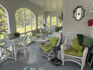 Une véranda couverte, meublée de meubles en osier, avec une table et une enseigne indiquant : « Scattered Fly ».
