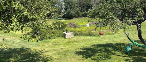 Un'area verde curata con alberi, una struttura in pietra e un'amaca.