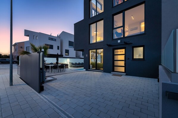 A modern building with a pool area, outdoor seating, and a reception desk.
