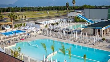 Un resort con diverse piscine, zone relax e uno sfondo montuoso.