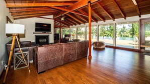 A spacious living area with a high ceiling, a fireplace, a large sofa, and a view of the outdoors. - Riverside Holiday Home Sleeps 10 (Anderson)