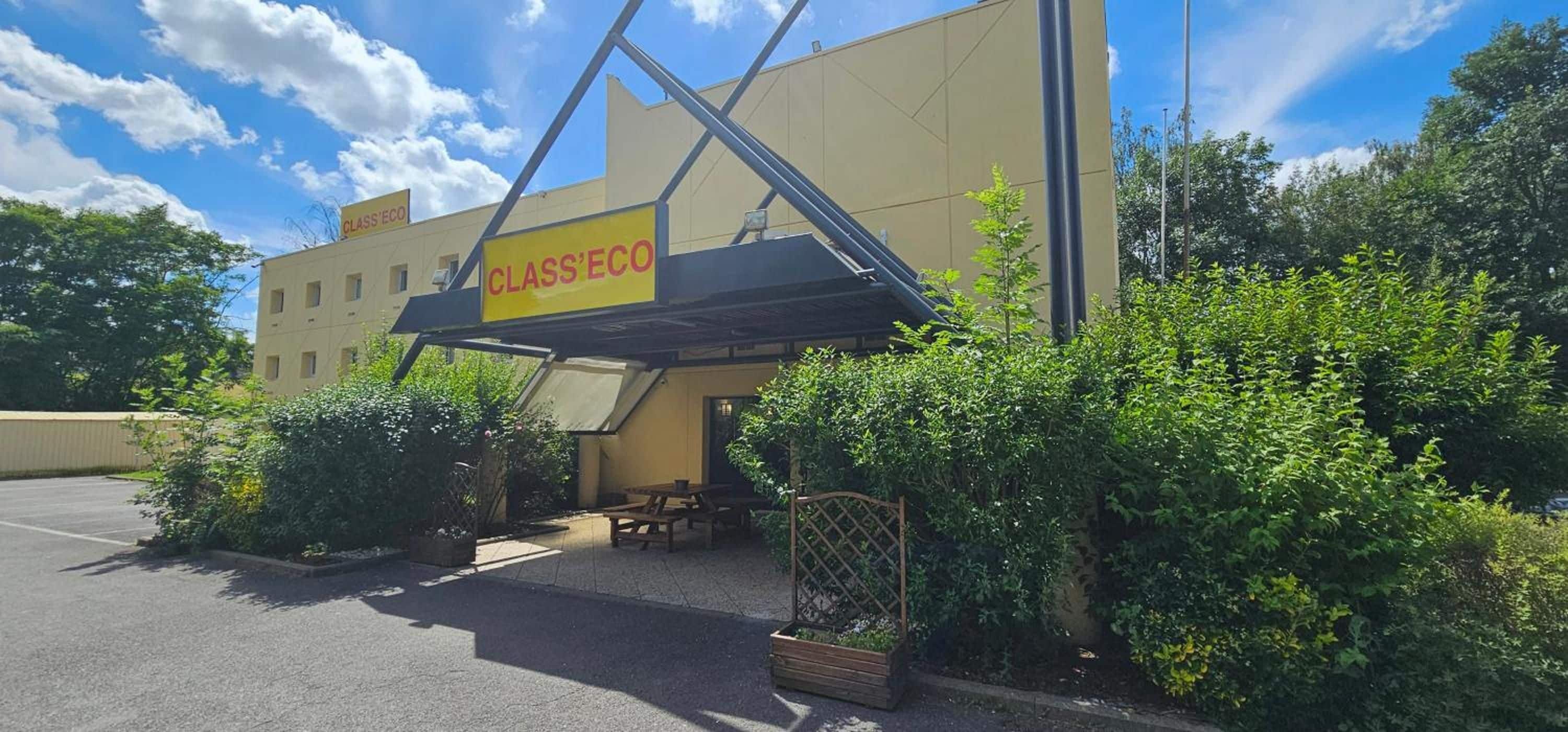 A building with a sign reading 'CLASS'ECO' and a covered outdoor seating area with tables and chairs.