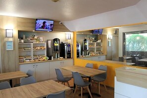 A modern dining area with tables, chairs, a television, and kitchen appliances. - Formule1 Charleroi (Charleroi)