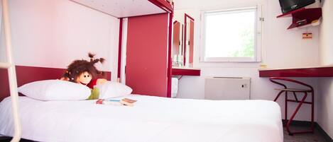 A single-bed room with a red and white color scheme, a television mounted on the wall, and a window providing natural light.