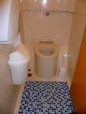 A small bathroom with a toilet, a trash bin, and a tiled floor. - Formule1 Charleroi (Charleroi)