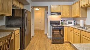 Una cucina con mobili in legno, elettrodomestici in acciaio inossidabile e un forno a microonde.