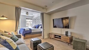 Una camera d'albergo moderna con un letto, una televisione, un divano e un piccolo tavolino.