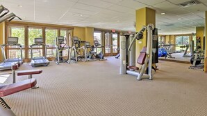 Una palestra con macchinari cardio, attrezzature per pesi e tappetini da allenamento.