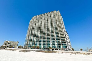 Ein Hochhaus mit mehreren Etagen, Balkonen und Blick auf den Strand.