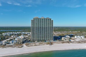 Ein Hochhaus-Hotel mit mehreren Etagen, ein Strand im Vordergrund und eine Aussicht auf die umliegende Landschaft.