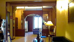A hotel lobby with a reception desk, seating area, and a large arched doorway leading to another room. - Toledano (Barcelona)