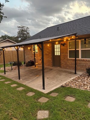 A brick house with a covered patio, a wooden fence, and a stone pathway. - 3-bedroom house in superb Conroe with cool AC and comfort (Conroe)