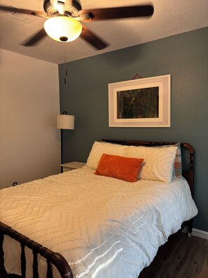 A bedroom with a bed, a ceiling fan, a wall-mounted lamp, and a framed picture. - 3-bedroom house in superb Conroe with cool AC and comfort (Conroe)