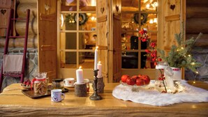 Una habitación acogedora con paredes de madera, una mesa con velas, un árbol de Navidad y vistas a un interior cálidamente iluminado.